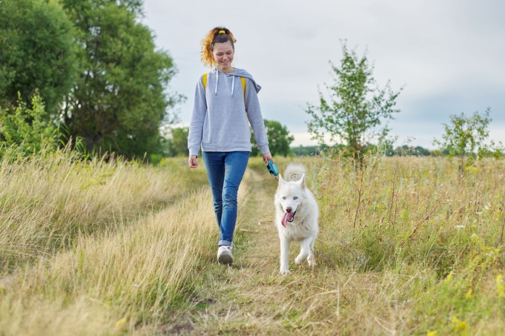 Tutora paseando con su perro por una zona tranquila y natural durante un paseo saludable y relajado.